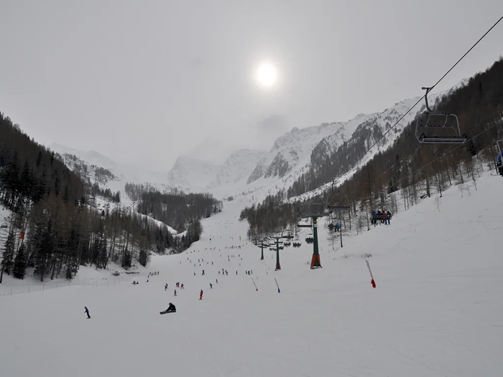 Nebelverhangenes Tal mit Sessellift und leerer Piste.